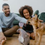 Man and girl enjoying quality time with their dog indoors, promoting family bonding.